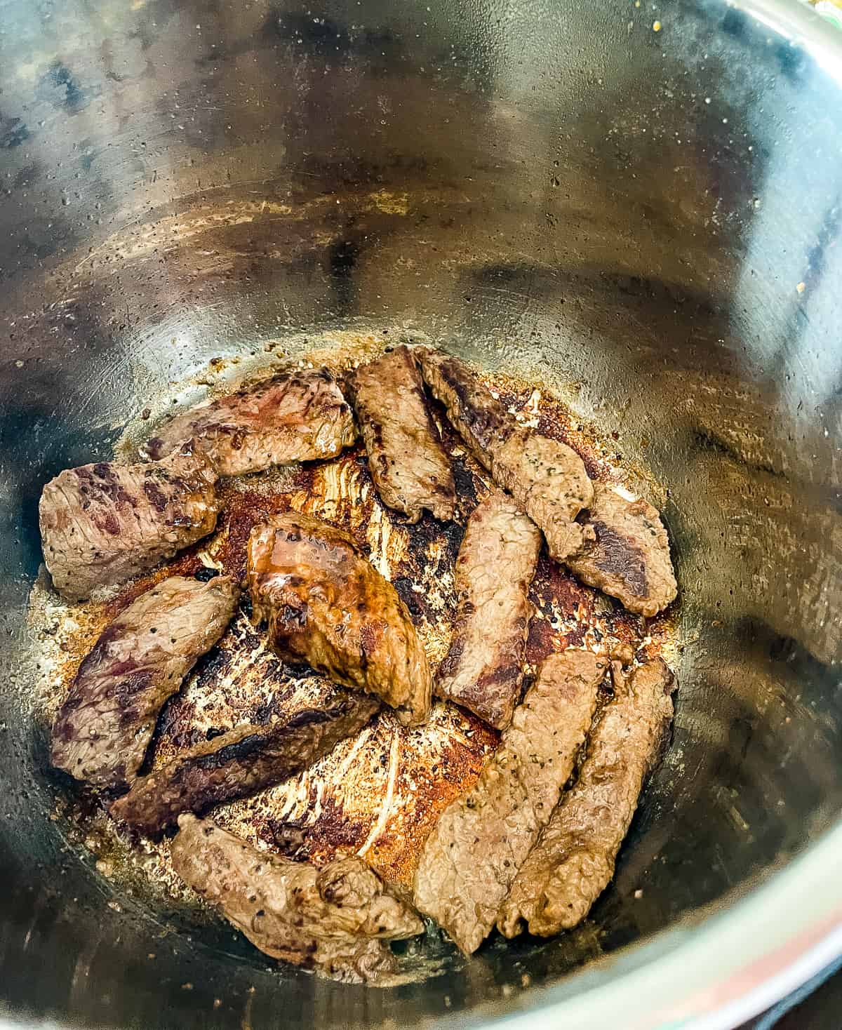browned strips of beef in the bottom of a pressure cooker
