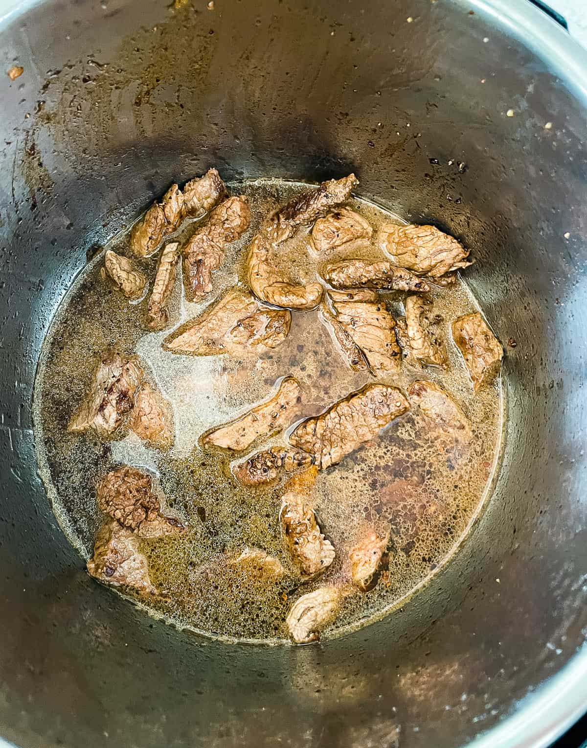 strips of meat and broth in an instant pot