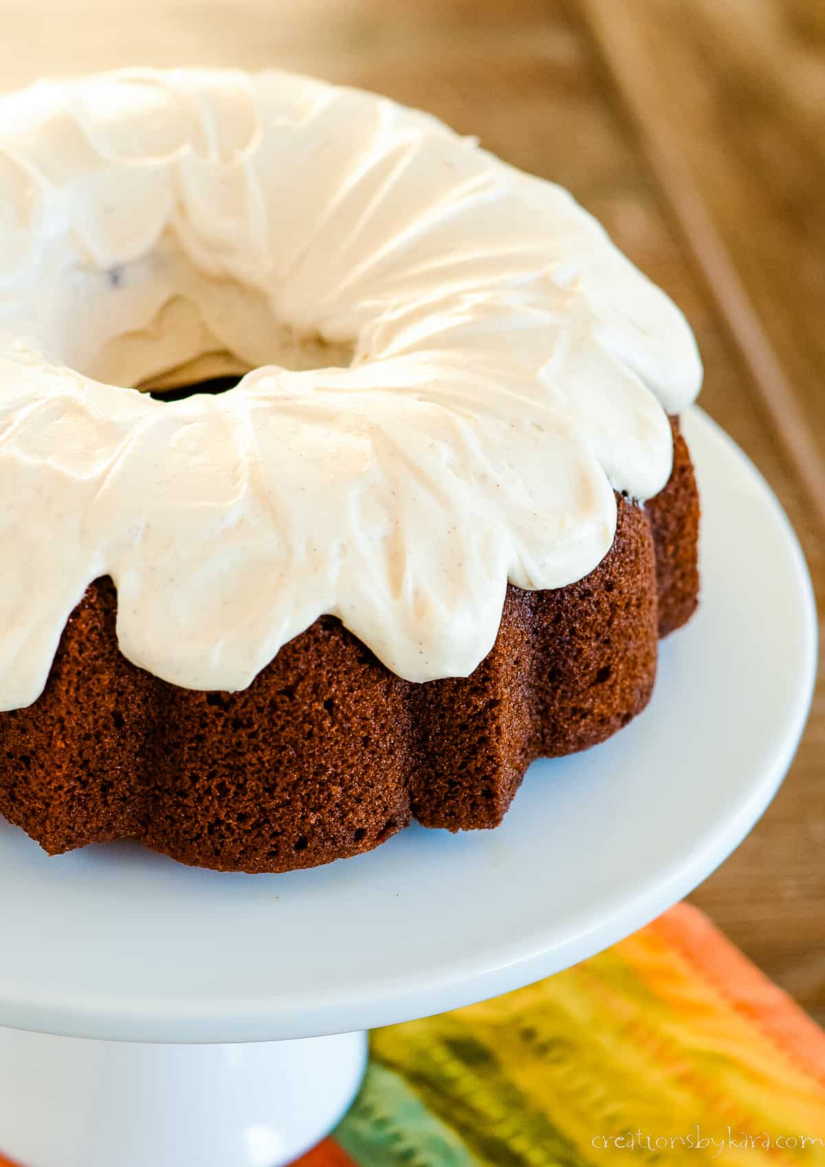 pumpkin bundt cake with cinnamon cream cheese frosting on a cake stand