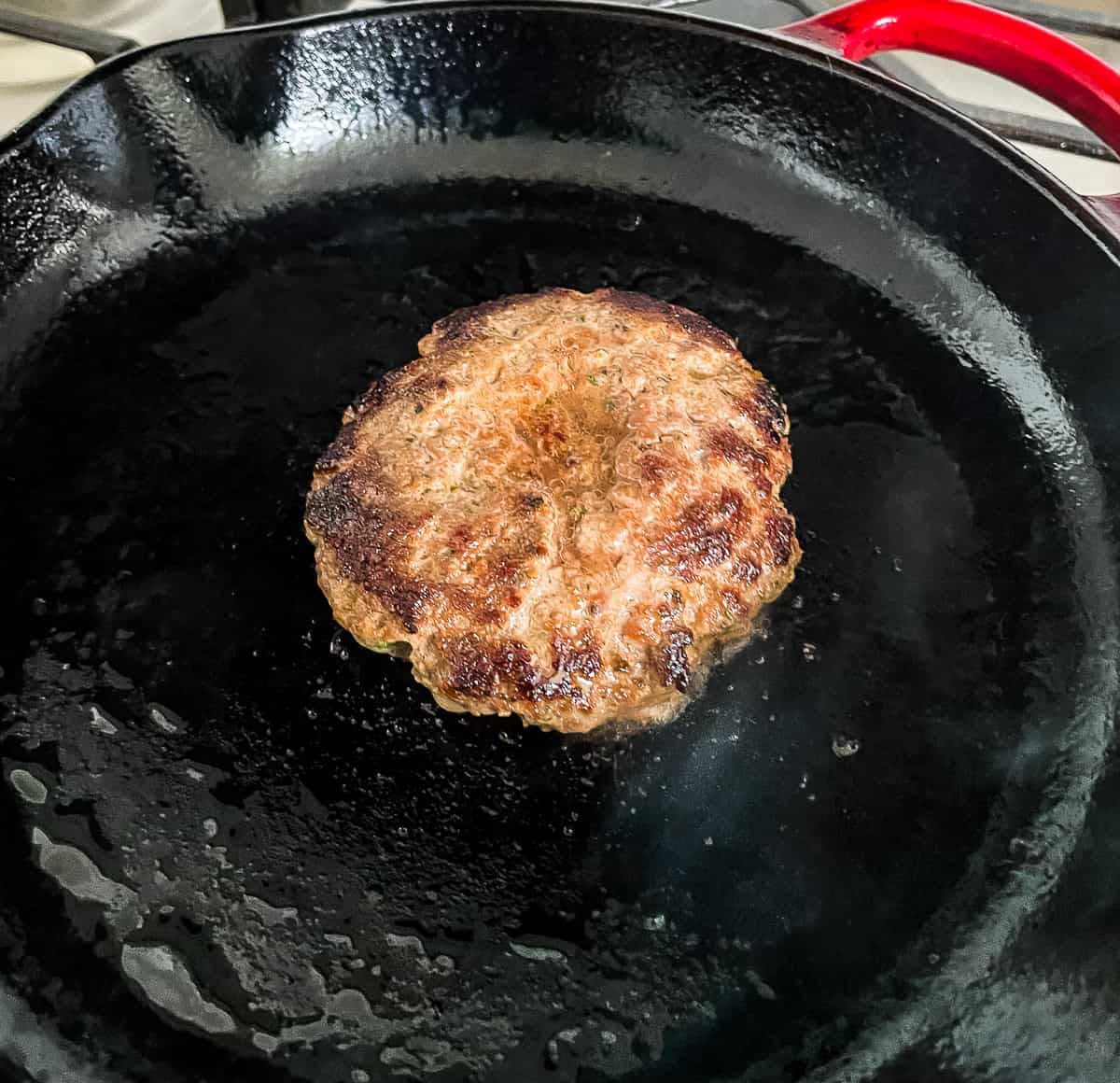 hamburger patty cooking in a skillet