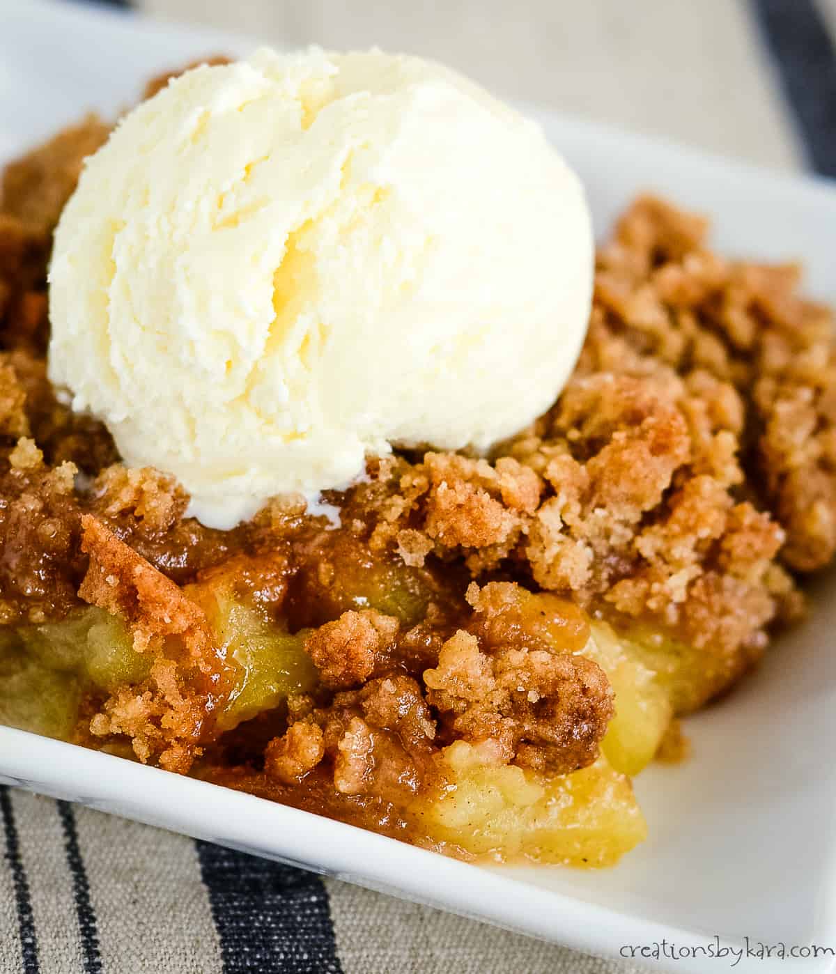close up of apple brown betty topped with vanilla ice cream