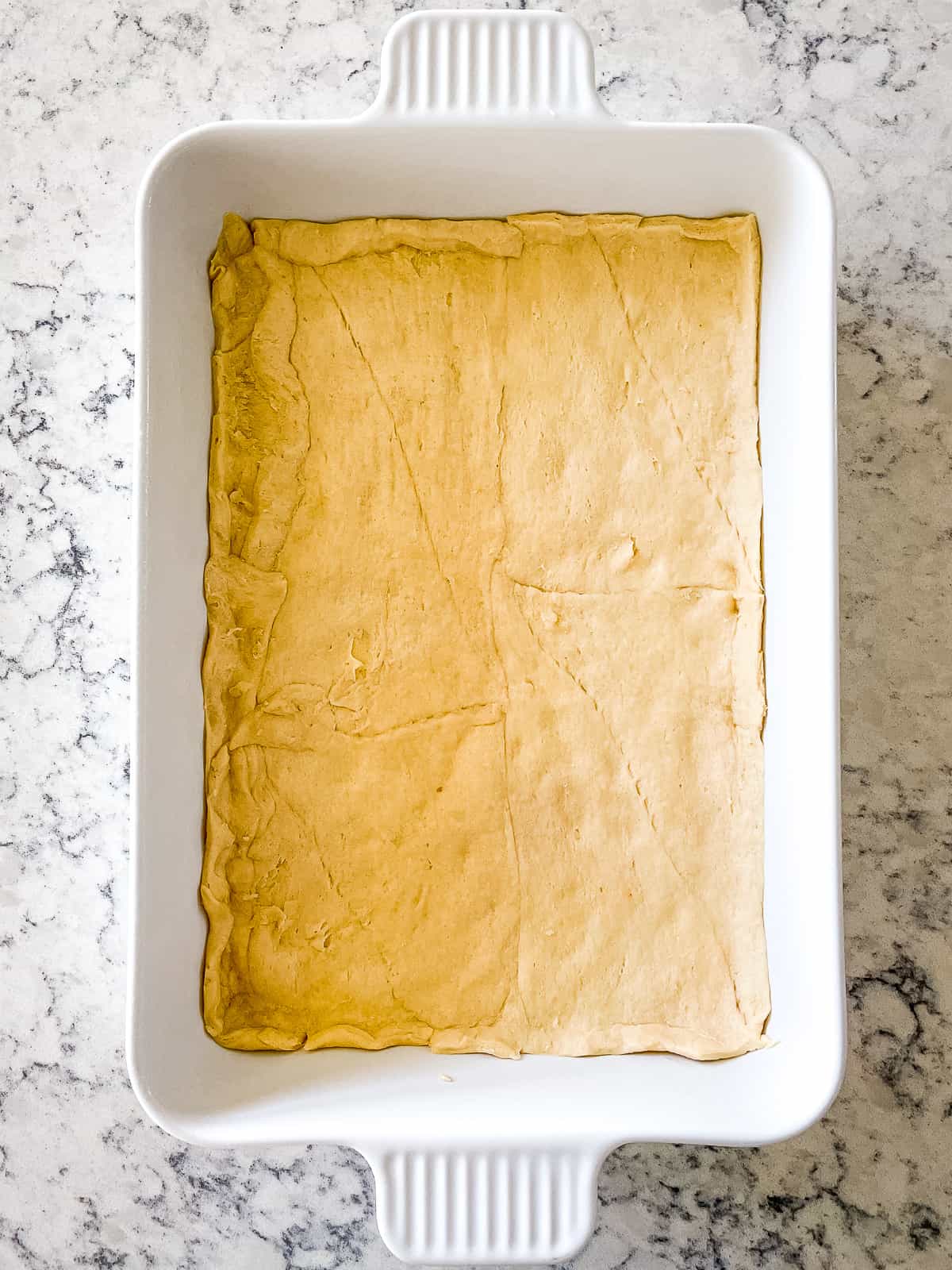 crescent roll dough pressed in the bottom of a baking dish