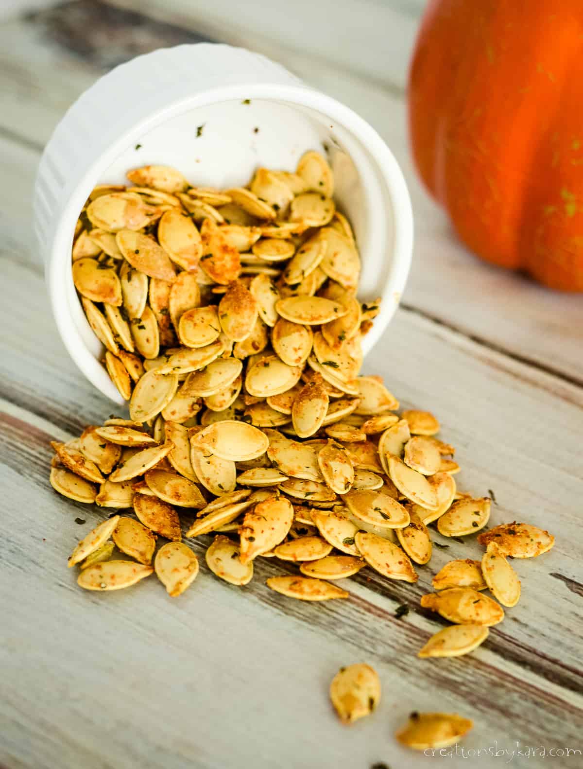 ranch flavored pumpkin seeds spilling out of a white bowl