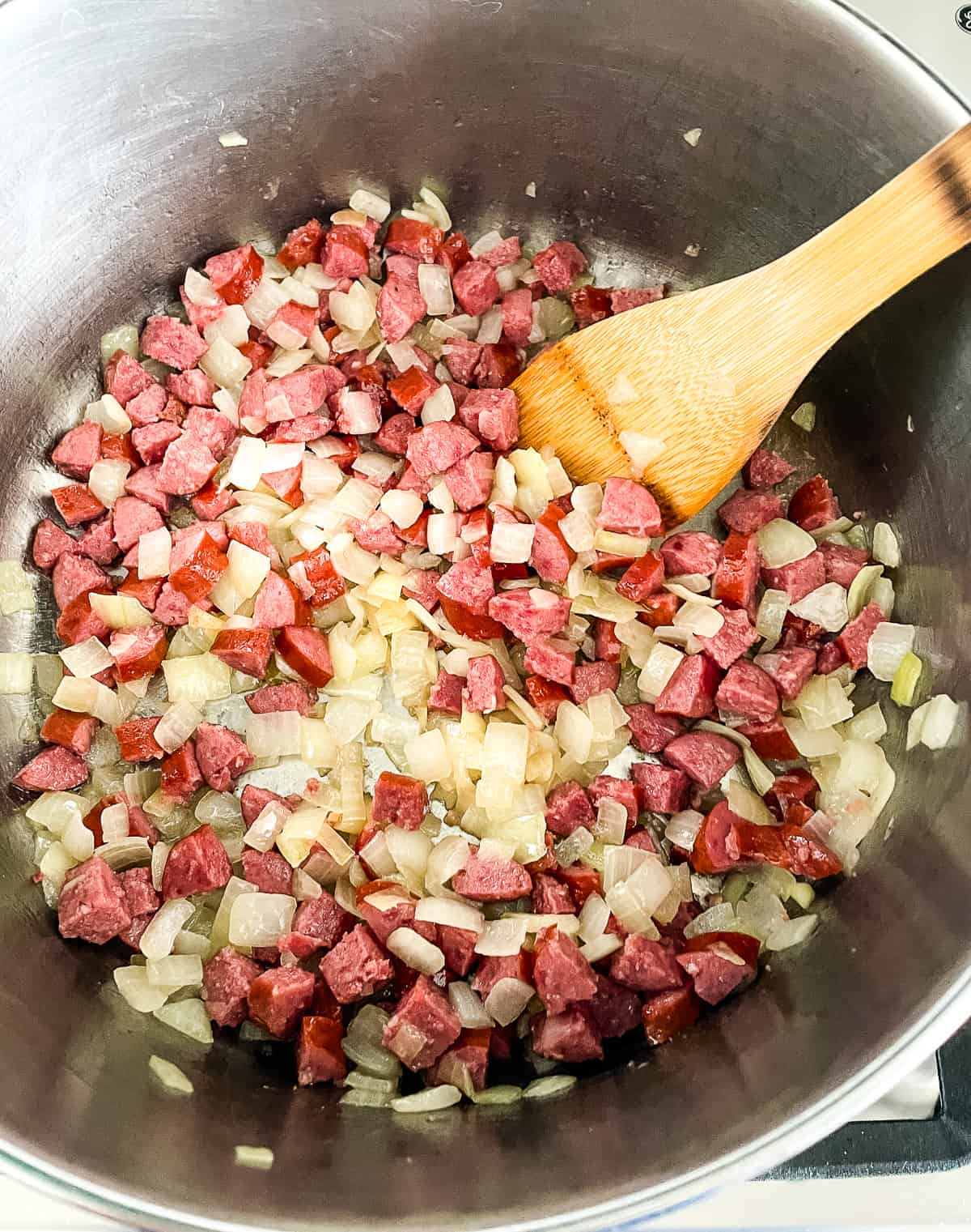 smoked sausage and diced onion in a soup pot