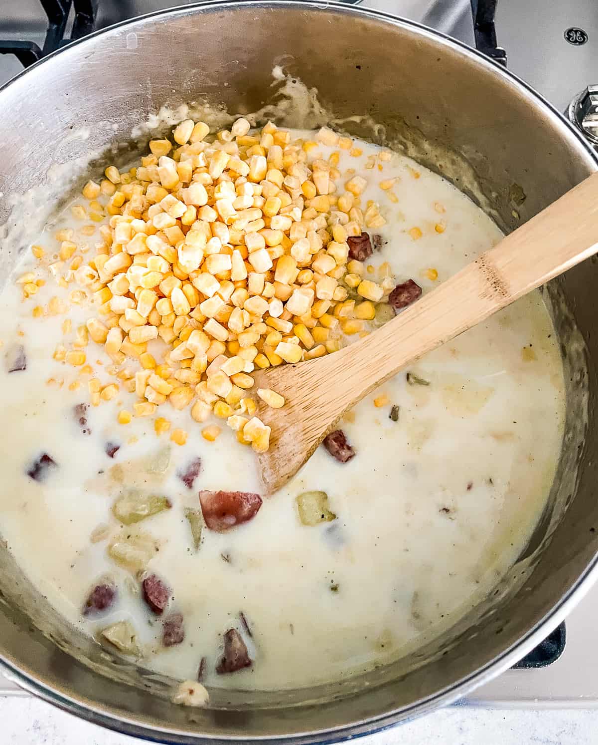 adding corn to sausage potato soup