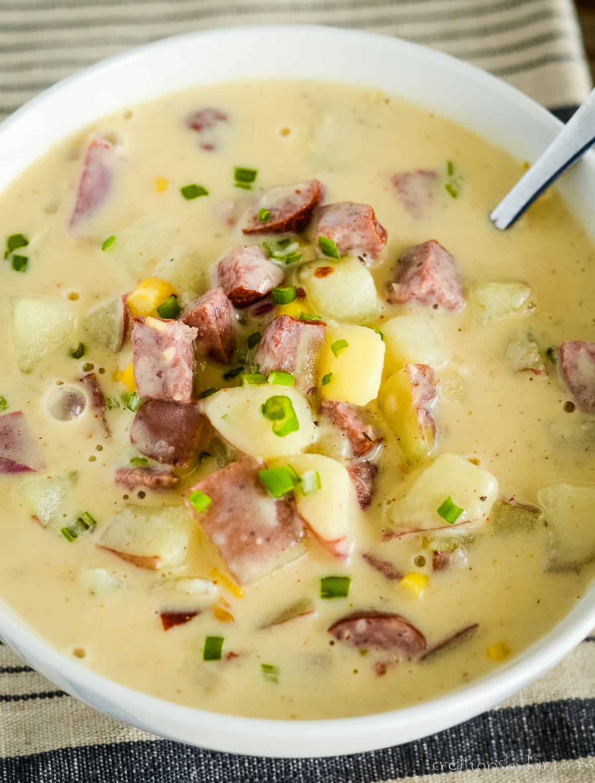 bowl of smoked sausage potato soup with a spoon in it