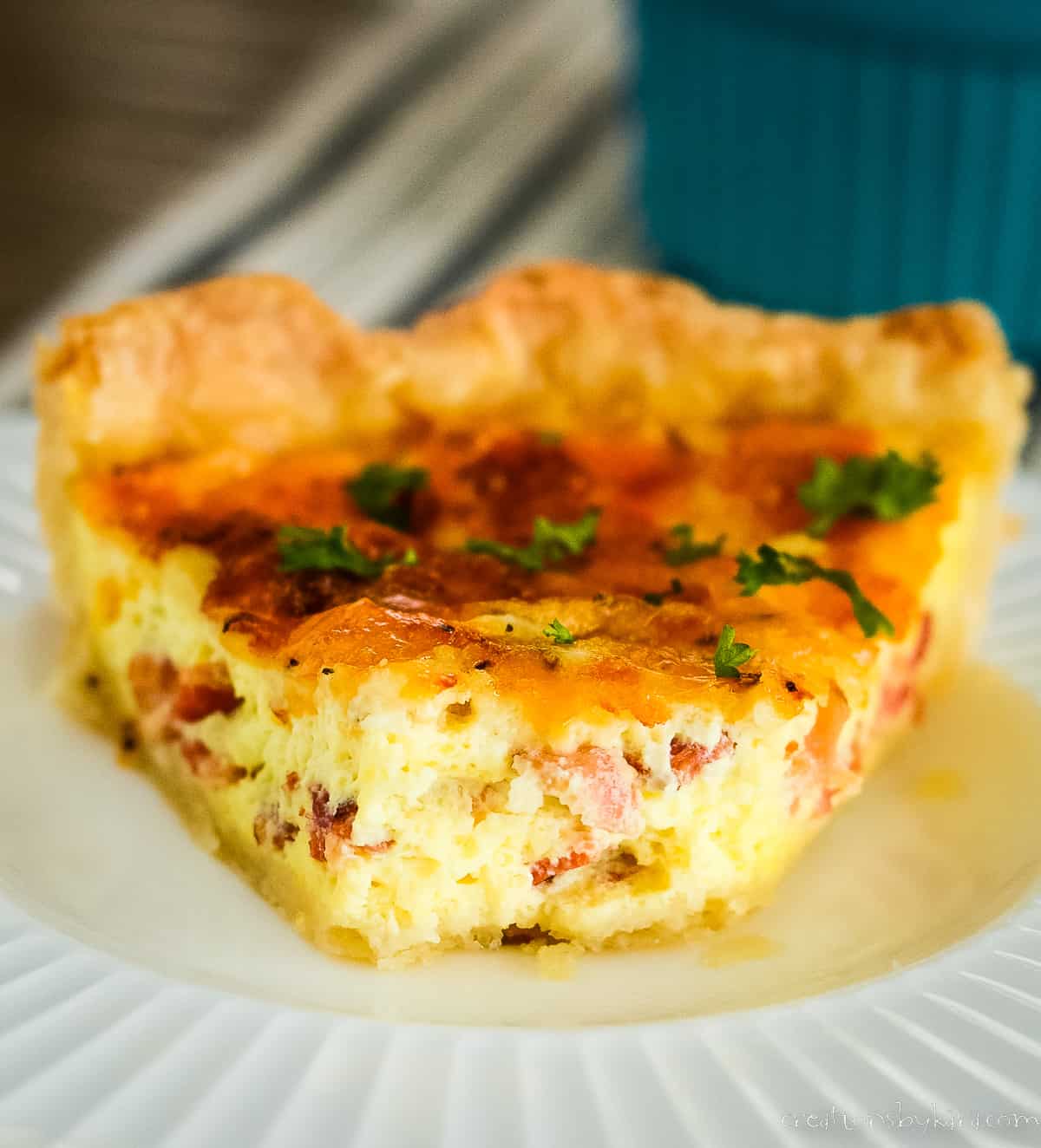 slice of bacon cheddar quiche with a bite taken out of it