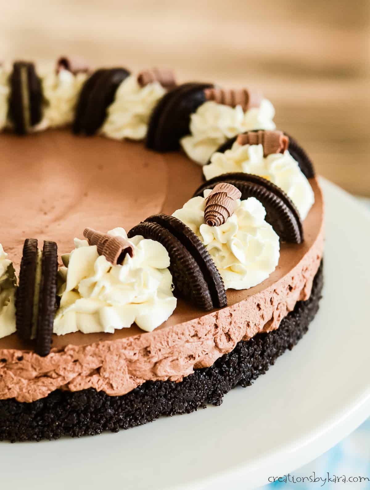 no bake chocolate mousse cake garnished with whipped cream, oreos, and chocolate curls