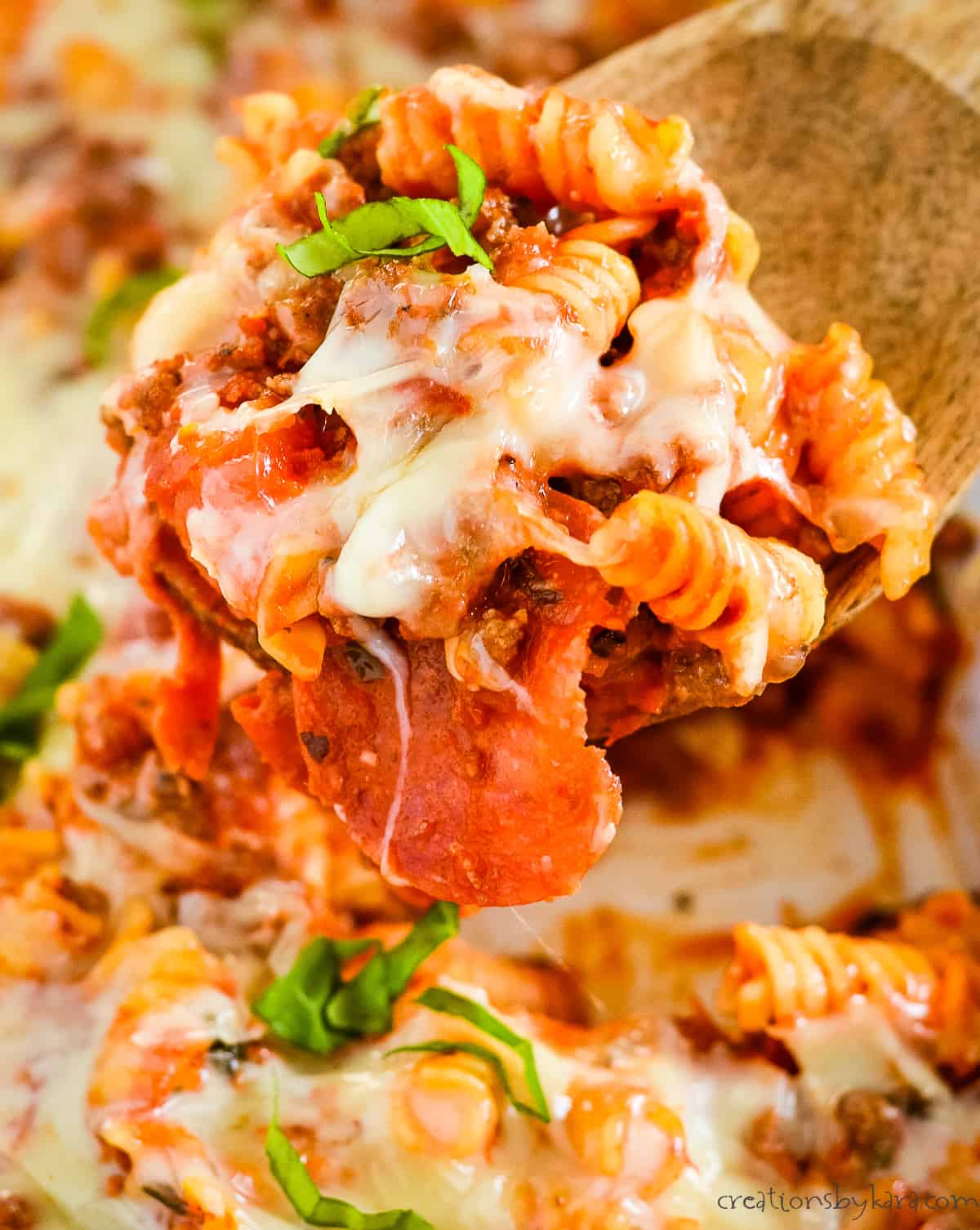 pepperoni pizza pasta casserole being scooped out of a pan