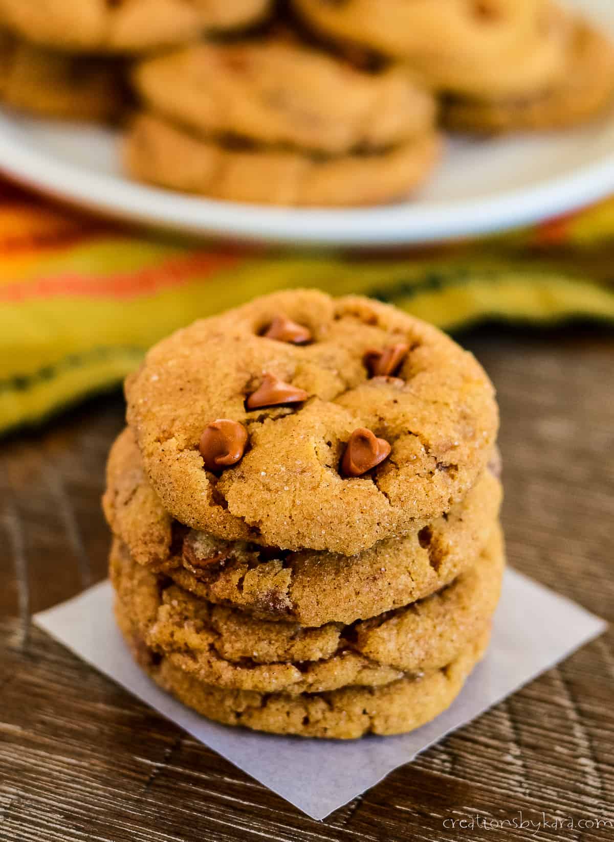 stack of pumpkin snickerdoodles with a plate of cookies in the background