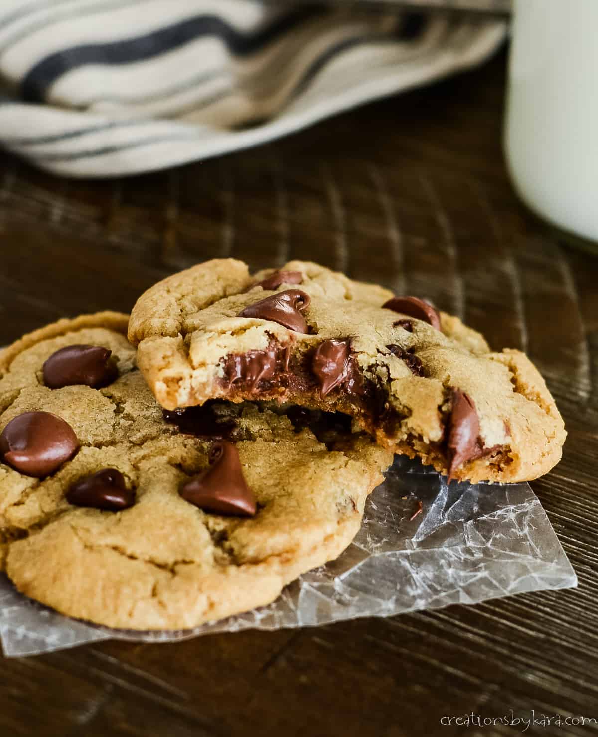 two warm chocolate chip cookies, one with a bite taken out of it