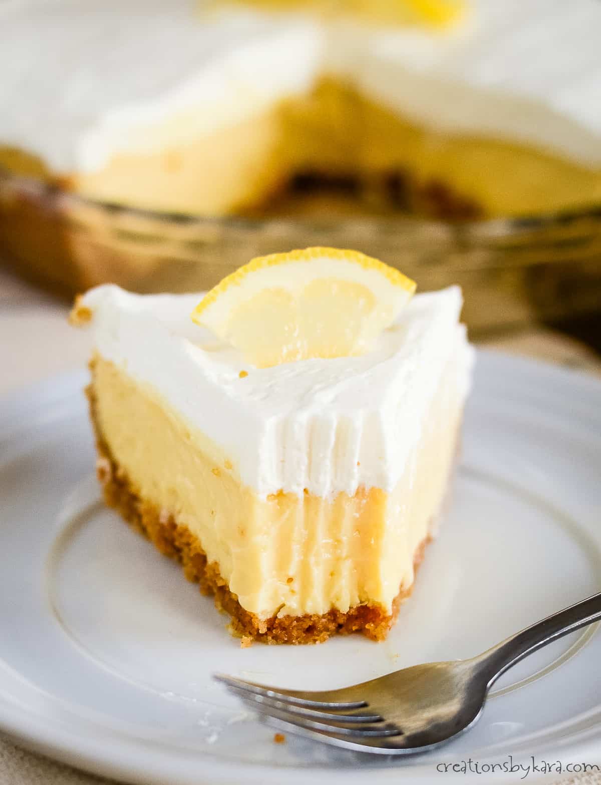 slice of lemon pie on a white plate with a fork