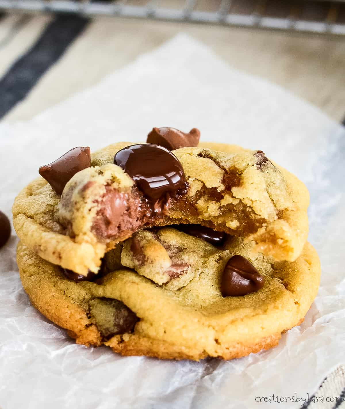 two warm chocolate chip cookies stacked, one with a bite taken out of it