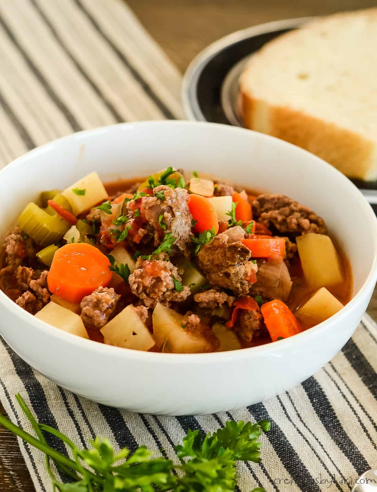bowl of ground beef stew with a plate of bread in the background