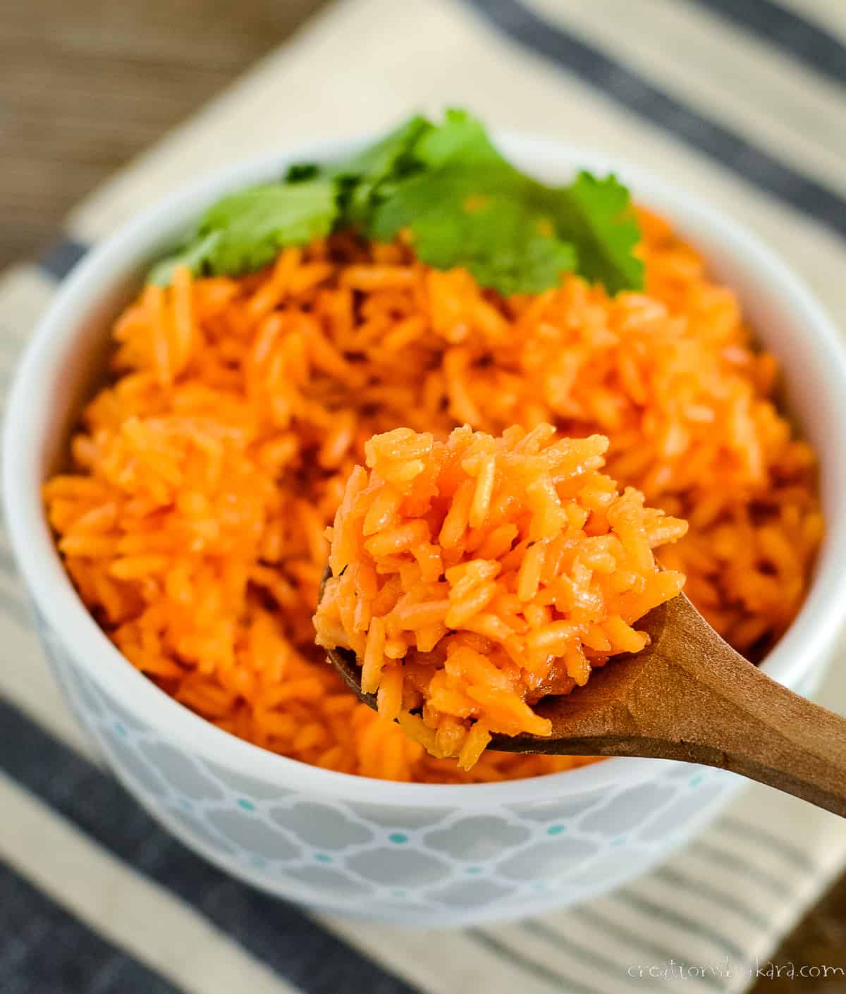 spoonful of mexican red rice held over a bowl of rice