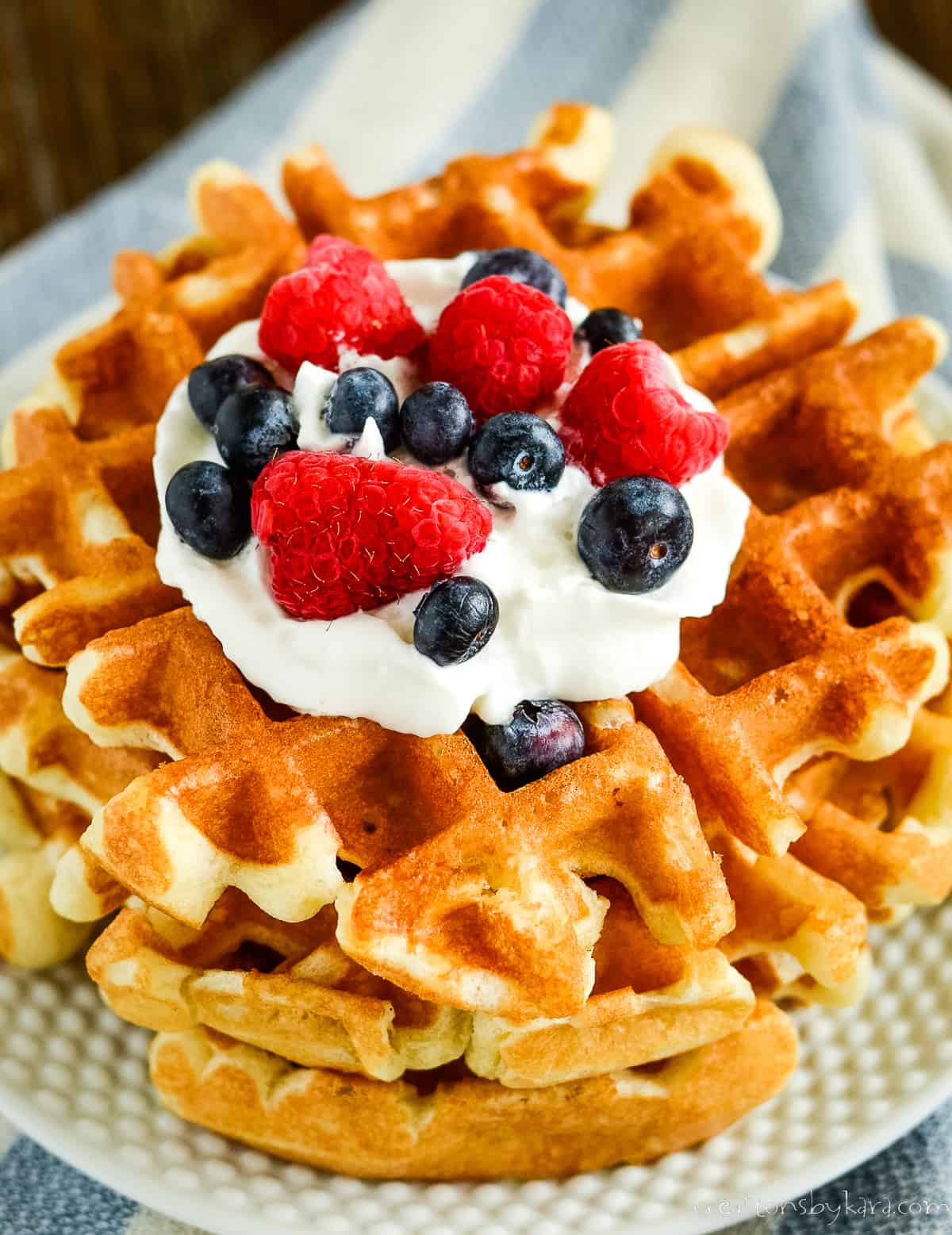 plate of sourdough waffles with whipped cream and fresh berries