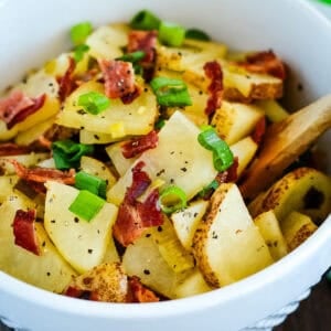 bowl of hot german potato salad with a wooden spoon