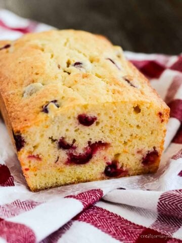 sliced loaf of cranberry cream cheese bread on a dish towel