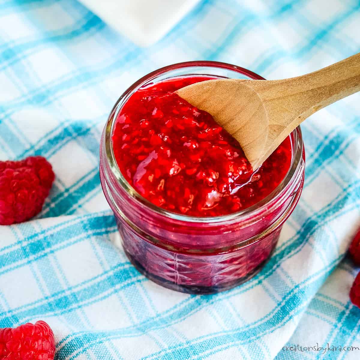 jar of homemade raspberry compote with a wooden spoon
