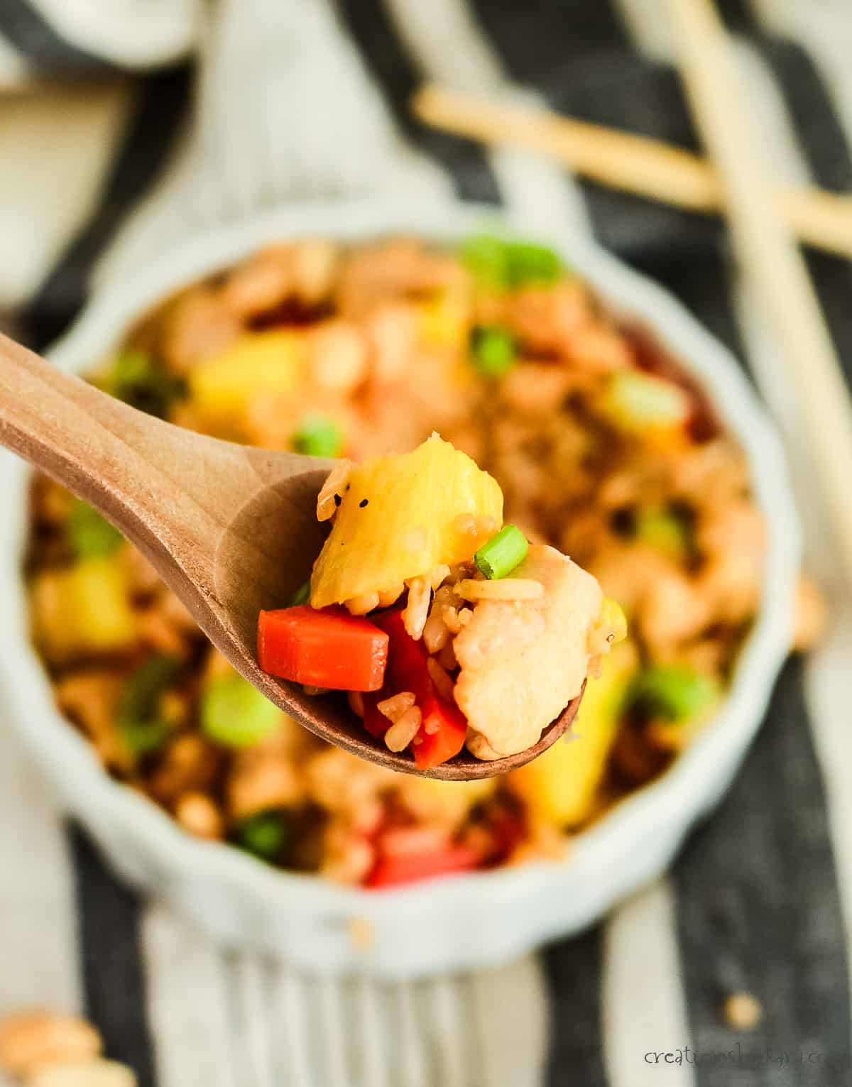 bite of chicken pineapple fried rice on a wooden spoon