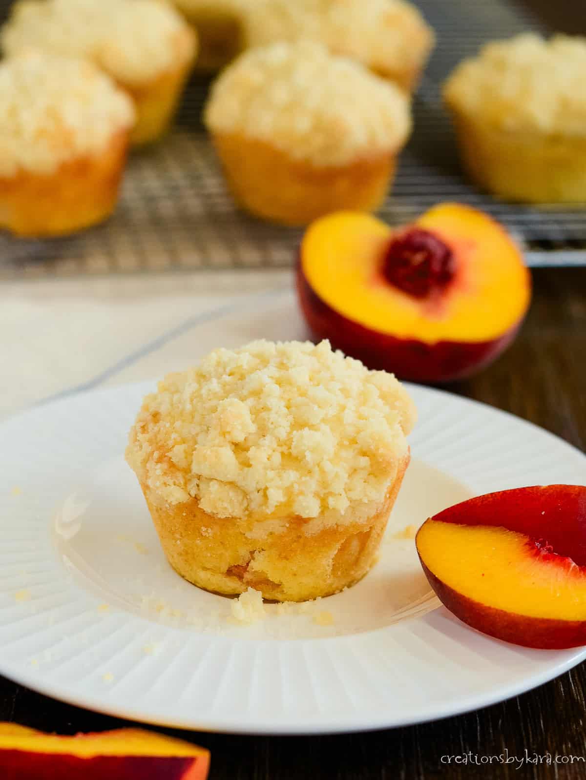 peach muffin with crumb topping on a white plate