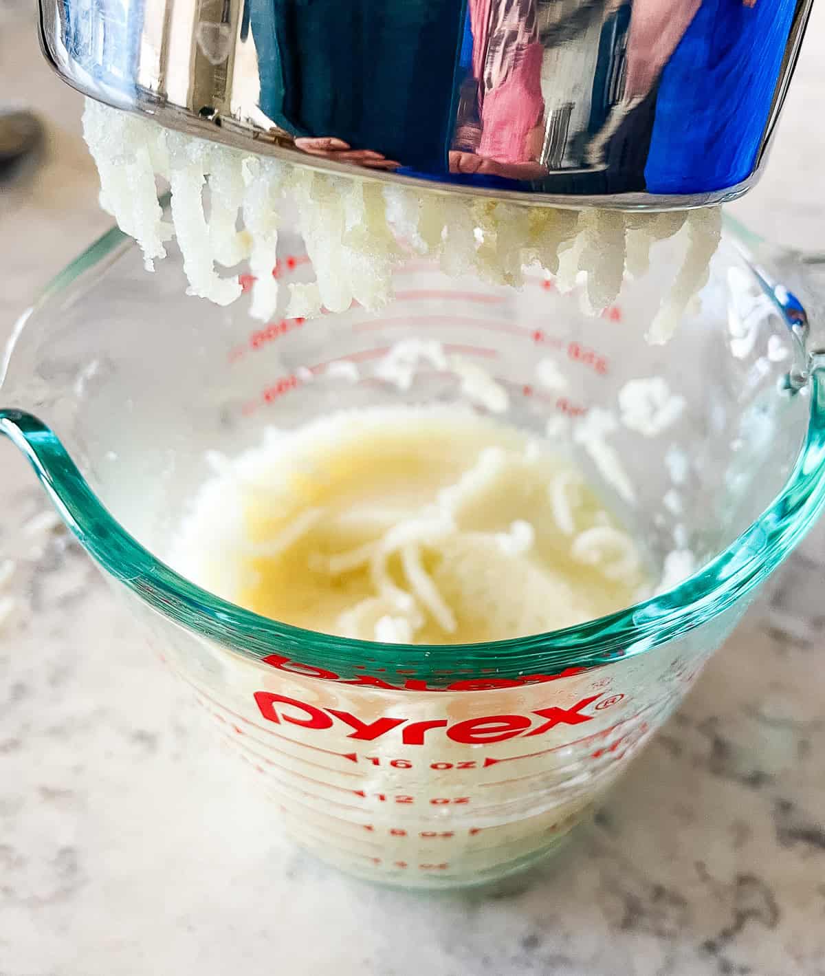 pressing potatoes through a ricer for potato donut recipe