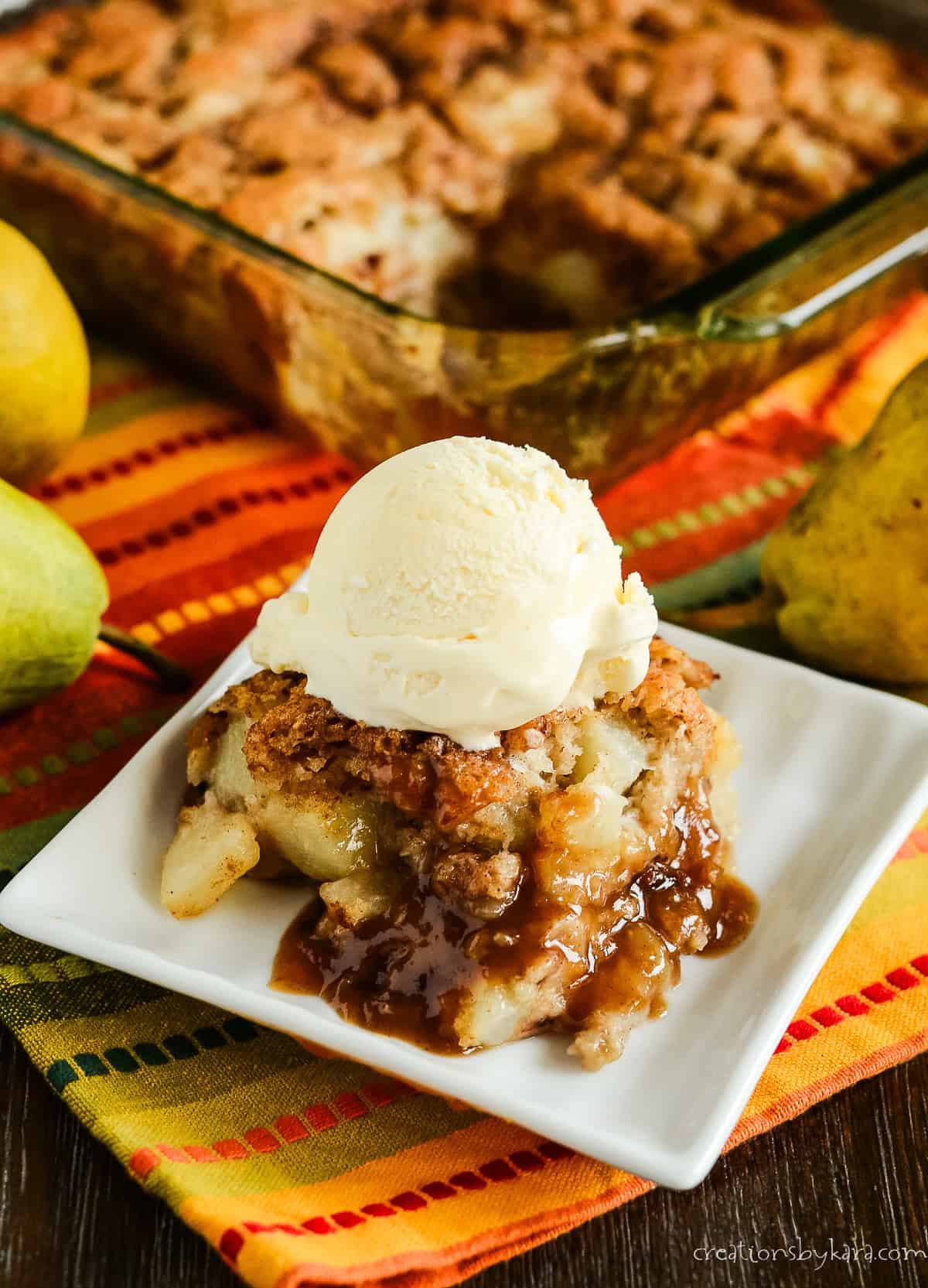 caramel pear pudding cake on a plate with a pan of cake in the background
