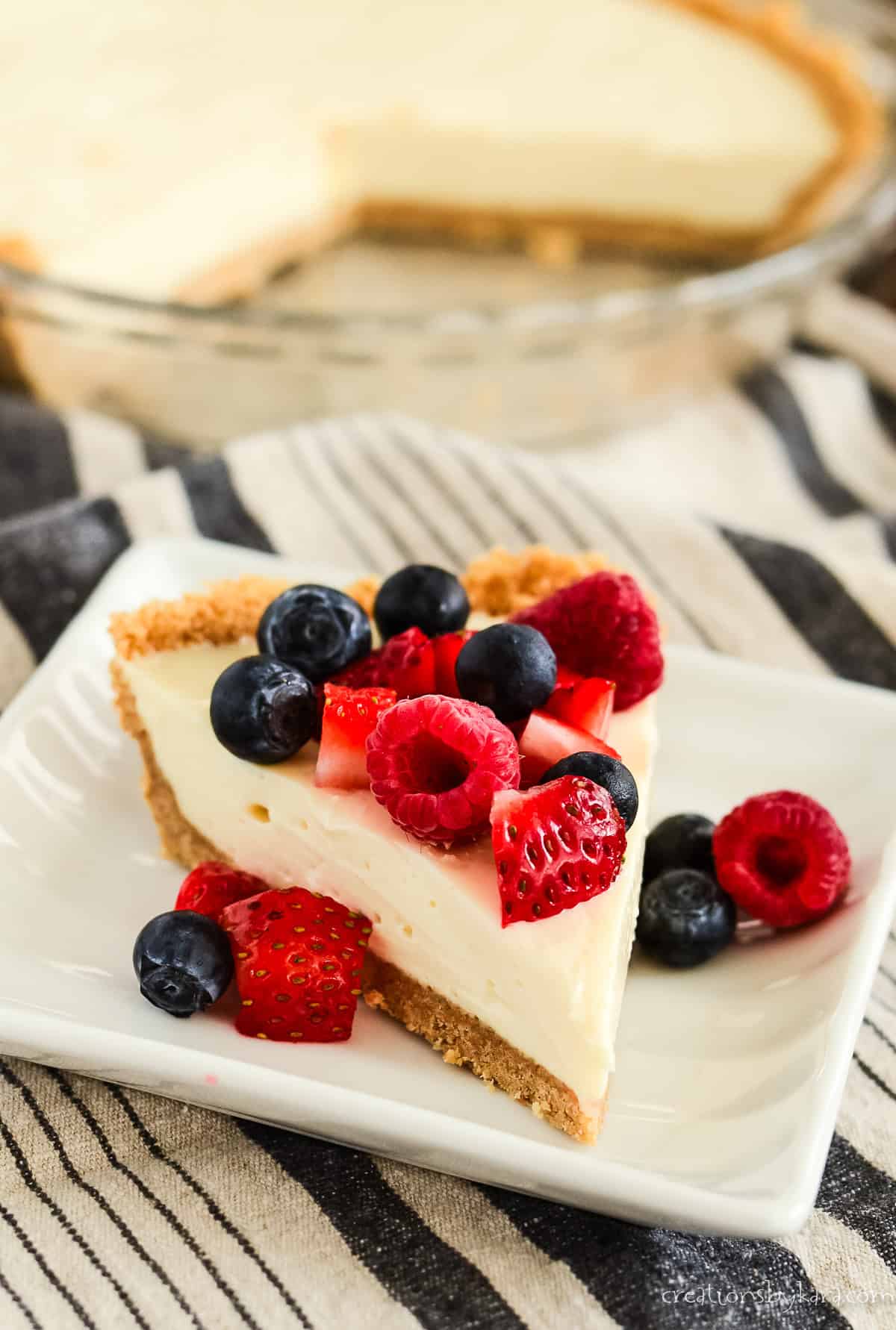 slice of condensed milk cheesecake on a plate with a sliced cheesecake in the background