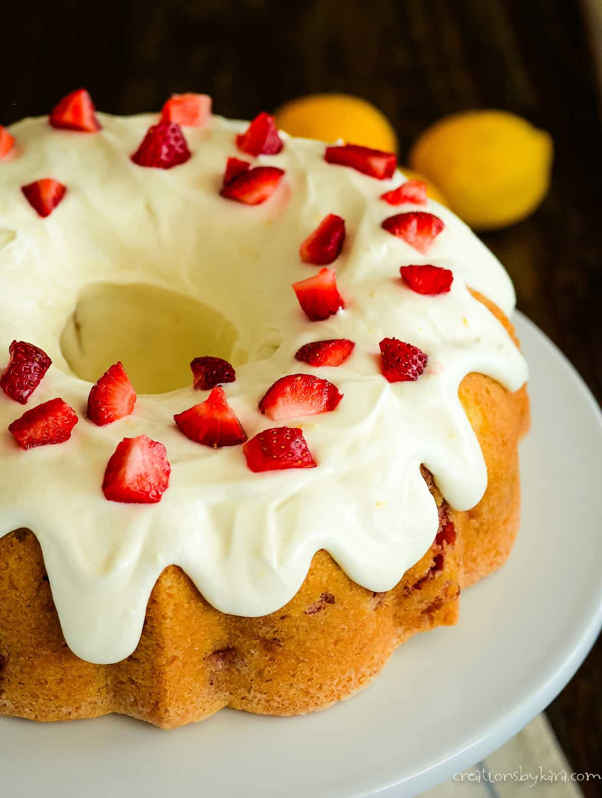 frosted strawberry lemonade bundt cake on a white cake stand