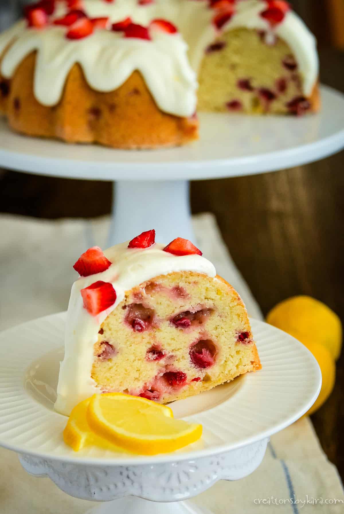 slice of strawberry lemonade pound cake with a sliced cake in the background