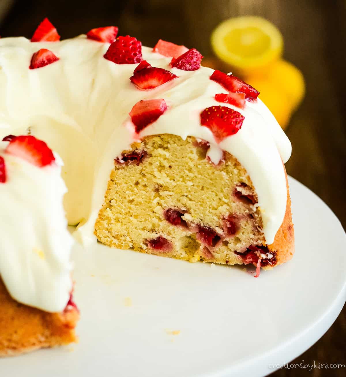 sliced strawberry lemonade pound cake on a white cake stand