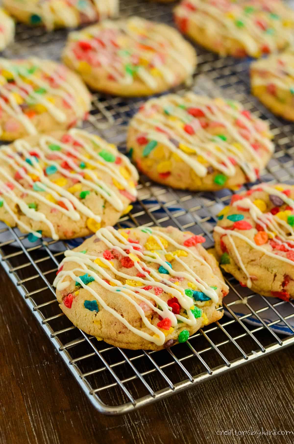white chocolate drizzled fruit pebbles cookies on a wire rack