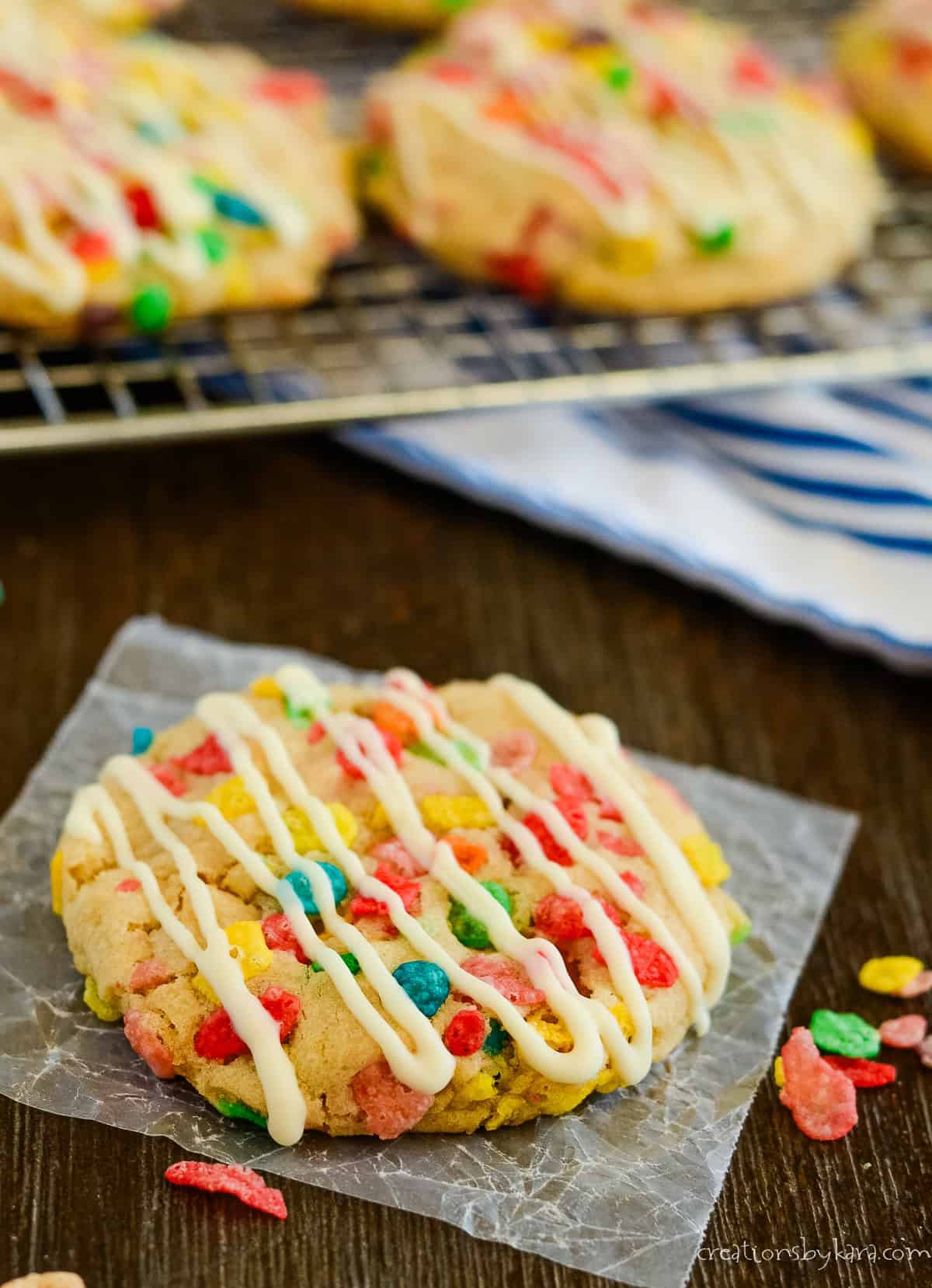 fruity pebbles cookie drizzled with white chocolate on waxed paper