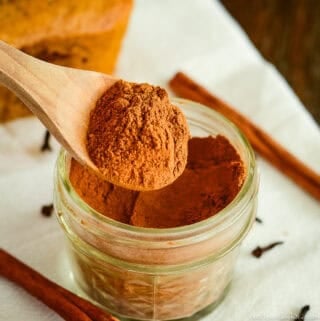 spoonful of homemade pumpkin pie spice being scooped out of a jar