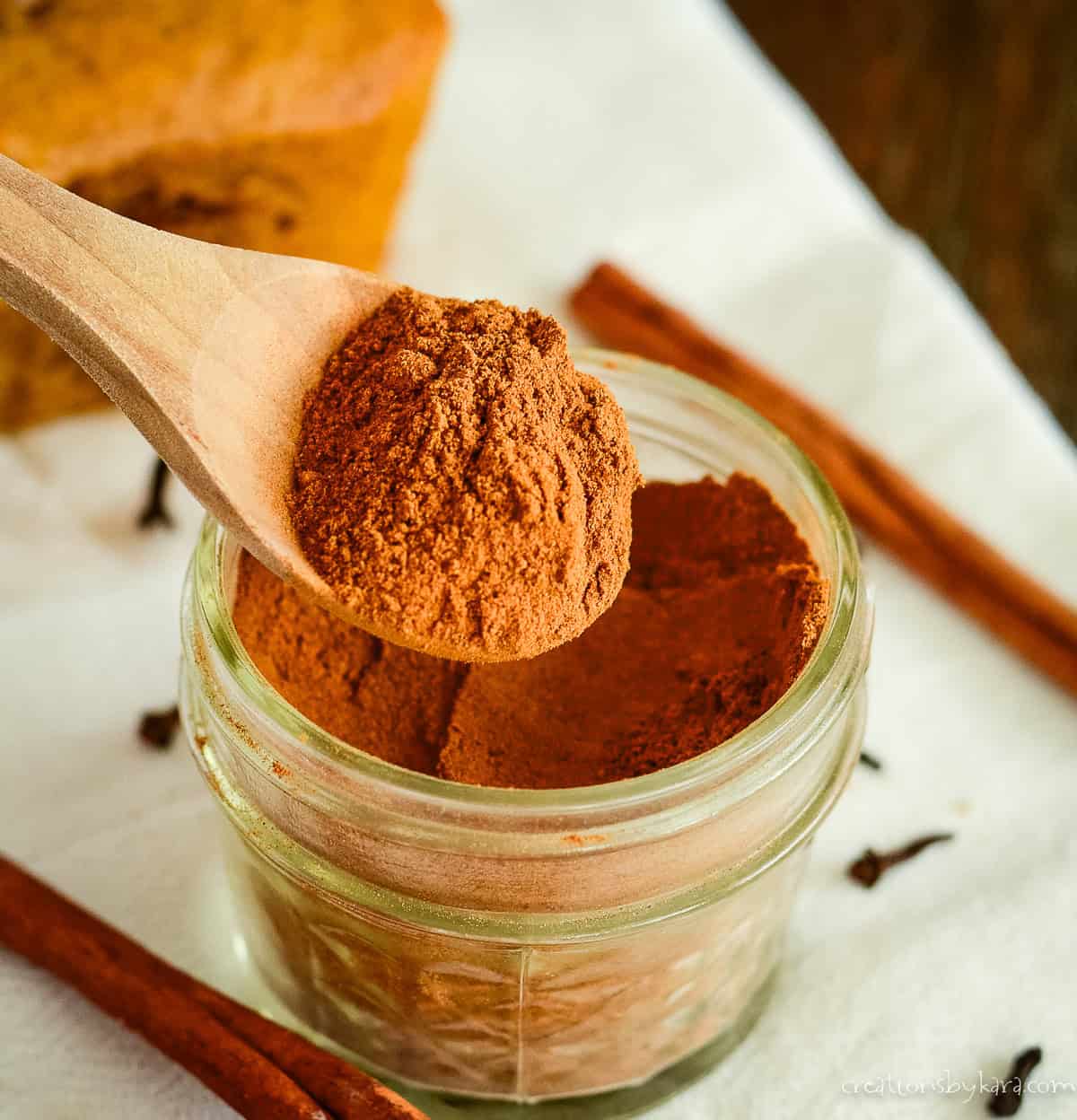 spoonful of homemade pumpkin pie spice being scooped out of a jar